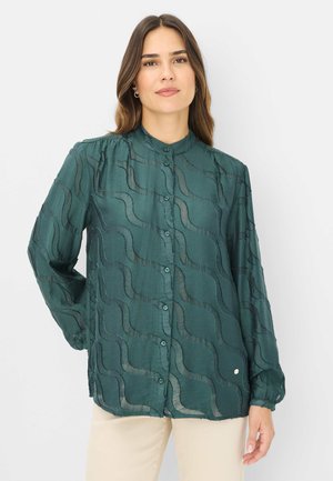 Emerald green, long-sleeve blouse with round collar and wave-pattern texture. Button closure and slight gathers at shoulders. Lightweight fabric.