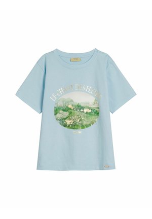 Jasnoniebieski t-shirt z krótkim rękawem i okrągłym dekoltem, z okrągłym kwiatowym pejzażem i tekstem "LE CHANT DES FLEURS" w kolorze złotym.