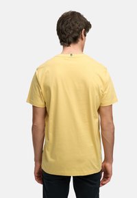 Herre t-skjorte med korte ermer i myk gul bomull, rund hals, flat kant og med et lite grønt merket på baksiden.