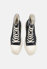 Hoge sneakers van zwart canvas met witte veters en stiksels. Beschikt over een stevige off-white zool en een afgeronde neus.