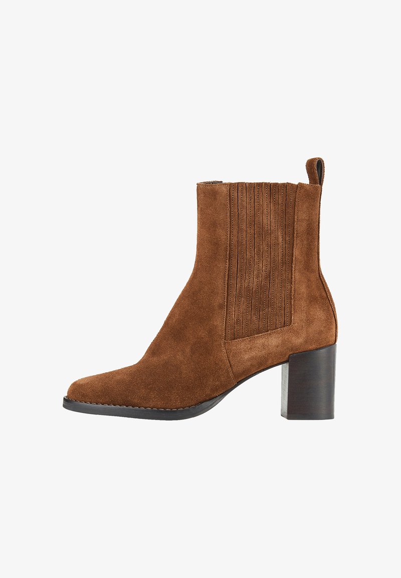 Bottine en suede marron avec un bout pointu, des panneaux latéraux élastiques cannelés et un talon épais. Dispose d'une languette pour un enfilage facile.