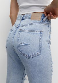 Jeans in denim chiaro sbiancati con vita alta, caratterizzati da orli sfrangiati, un'etichetta in pelle sul retro e due tasche a toppa.