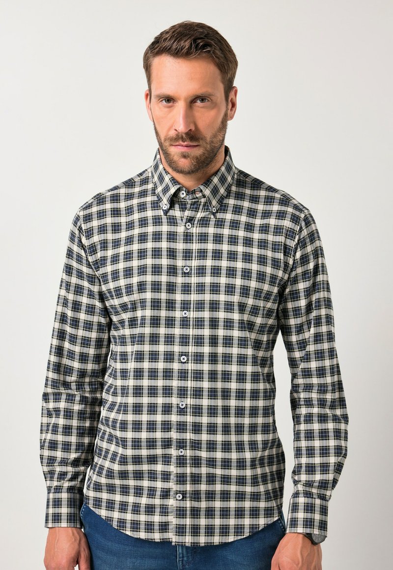 Camicia a quadri nei colori beige, blu navy e bianco. Caratterizzata da colletto a bottone, maniche lunghe e orlo arrotondato. Realizzata in tessuto a trama.
