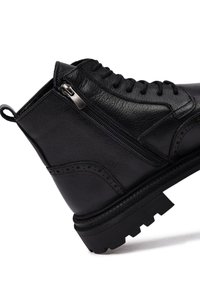 Zwarte leren enkelboots met een semi-glanzende afwerking, voorzien van een zijrits, veteroversluiting, textuur bovenwerk en robuuste zool.