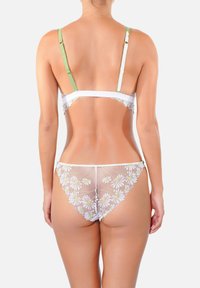 Ensemble de lingerie en dentelle blanche avec broderies florales, doté de fines bretelles vertes et d'une texture transparente. Le design met en valeur des motifs floraux dans le dos.