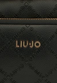 Schwarze strukturierte Leder-Handtasche mit geprägtem Markenlogo und goldfarbenen Beschlägen sowie einem Reißverschluss.