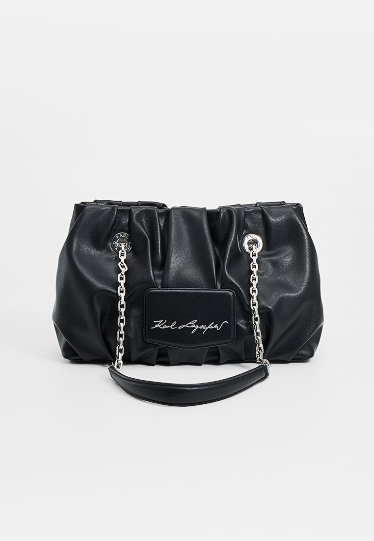 Bolso de mano de cuero negro con diseño fruncido, cadena y correa plateadas, que presenta un parche rectangular con logotipo y texto en cursiva. Textura suave.