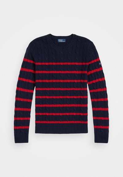 Pull en maille côtelée bleu marine avec des rayures rouges horizontales. Présente un col et des poignets côtelés. Étiquette de marque sur la manche gauche.