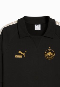 Fekete póló ing gallérral, arany logókkal: "KING" és FC Salzburg. Fehér és arany mintázott csíkok a vállakon. Pamutkeverék anyag.