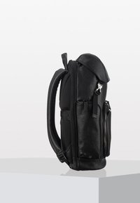 Zaino in pelle nera con un design strutturato, caratterizzato da un cappuccio superiore, pannello laterale in rete e svariati scomparti con zip per la conservazione.