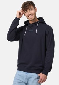 Donkerblauwe hoodie met een verstelbare capuchon, ribgebreide manchetten en onderrand. Bevat een klein rechthoekig logopatch op de borst. Zachte stofstructuur.