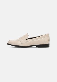 Mocassini in pelle beige con motivo a coccodrillo, suola nera piatta e texture liscia. Presentano una fascia rialzata sulla parte anteriore.