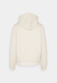 Sudadera crema con capucha ajustable, puños acanalados y dobladillo inferior con un logo blanco. Hecha de una tela suave y texturizada.