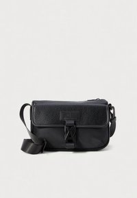 Mala tiracolo preta com aba em pele texturada, corpo liso, alça ajustável e fecho de encaixe proeminente. Design minimalista com detalhe do logótipo.