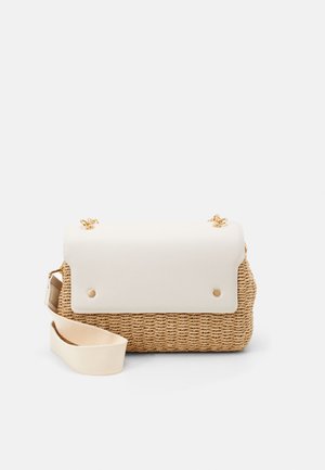 Sac d'épaule en paille tissée avec rabat blanc lisse, détails en chaîne dorée et bandoulière ajustable en tissu crème sur fond uni.