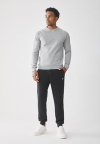 Gray long-sleeve sweatshirt paired with black joggers, featuring a subtle logo, and white sneakers. Soft fabric, relaxed fit, and cuffed hems.