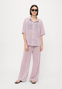 Conjunto de dos piezas ligero de punto en suave lavanda, que incluye una camisa de botón de manga corta y pantalones de pierna ancha con textura vertical.