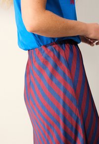 Gonna a righe rosse e blu in tessuto morbido con una vita elastica, che mostra una vista ravvicinata del motivo e della trama del tessuto.