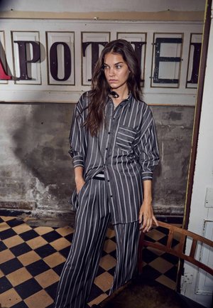 Gray striped shirt and matching wide-leg pants in lightweight fabric. Features button front, loose fit, and chest pocket. Wood accents visible.
