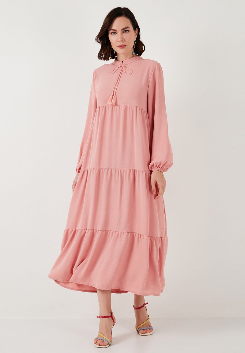 Robe rose à manches longues avec un col haut, détails à nouer et design à volants. Tissu doux, manches froncées et silhouette fluide.