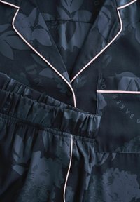 Navy pajama set with floral pattern, featuring a button-up top with a pocket and pale pink piping, and elastic waistband shorts.