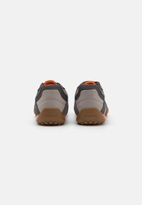 Gray and orange sneakers with mesh upper, rubber sole, and rounded heel. Features include a logo on the heel and contrasting accents.
