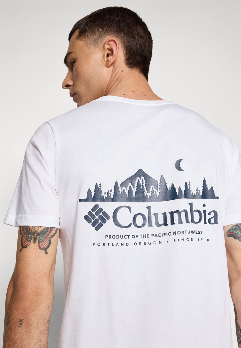 Weißes T-Shirt mit einem marineblauen Grafikmotiv eines Berges und Bäumen auf der Rückseite, mit "Columbia" und Text darunter. Kurze Ärmel, Rundhals.
