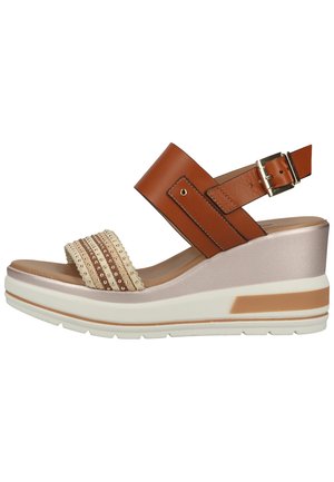 Wedge-Sandale mit einem braunen Lederfesselriemen mit Schnalle, einem strukturierten beigen Riemen und einer weißen Plattformsohle mit braunen Akzenten.