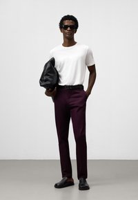 Borsa in pelle nera, t-shirt bianca a maniche corte, pantaloni su misura bordeaux, cintura nera, scarpe slip-on nere e occhiali da sole. Design semplice e moderno.