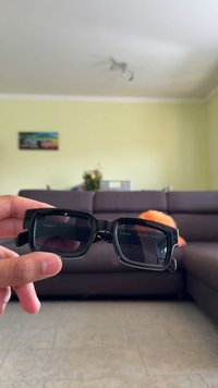 Μαύρα γυαλιά ηλίου με τετράγωνο σκελετό και σκούρους φακούς. Παχιά μπράτσα και ξεχωριστός, γωνιώδης σχεδιασμός. Καθαρή σήμανση στο εσωτερικό ενός φακού.