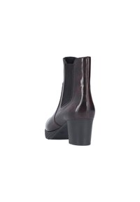 Bottine en cuir bordeaux avec un talon épais, des panneaux latéraux élastiques, une texture lisse et un bout rond. Présente un logo à l'arrière.