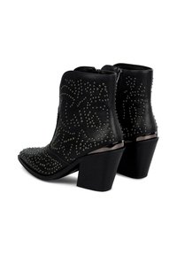 Botines negros de cuero con detalles de tachuelas, punta afilada y tacón cuadrado. Con cremalleras en la parte posterior.