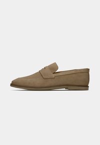 Beige Wildleder Slipper mit runder Zehenform, gestickten Details und einem kleinen Riemen über dem Obermaterial. Flache Gummisohle, minimalistisches Design.