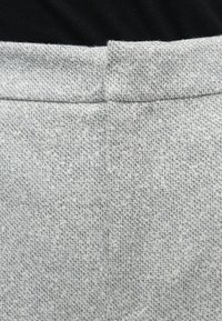 Grå tekstureret stof med et subtilt mønster, forsynet med en ren linning. Materialet har en blød og let fnugget overflade.