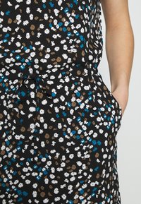 Robe en tissu noir avec un motif floral blanc, marron et bleu. Comprend une ceinture à la taille et des poches latérales. Texture lisse.