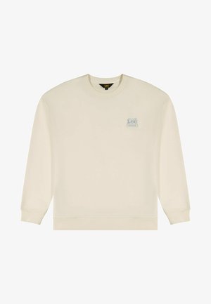 Bluza w kolorze kremowym z długimi rękawami, ściągaczami na mankietach i dole. Na lewej stronie klatki piersiowej znajduje się małe niebieskie logo. Miękka tekstura tkaniny.