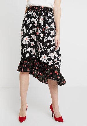 Floral midi skirt in black with white and red flower patterns, featuring a ruffled hem and a fitted waistband. Paired with red high heels.