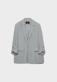 Blazer gris clair à un bouton avec revers crantés, deux poches à rabat, une poche poitrine et manches retroussées avec pattes boutonnées.