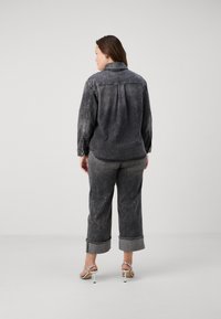 Siva denim srajca z udobnim krojem, z ovratnikom, gumbnim zapiranjem in dolgimi rokavi. V kombinaciji z ujemajočimi sivimi skrajšanimi hlačami.
