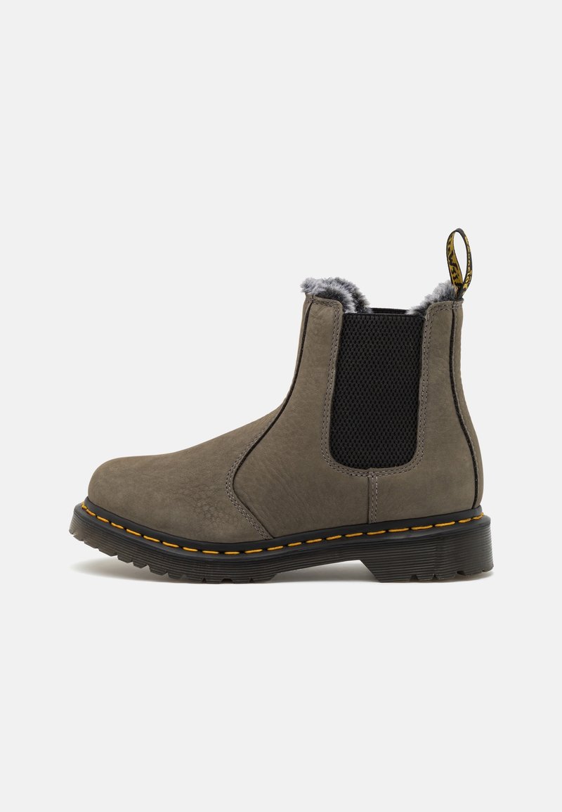 Botte Chelsea en cuir marron avec un panneau latéral élastique noir, des surpiqûres jaunes sur la semelle noire, et une doublure en fourrure grise visible au niveau de la cheville.