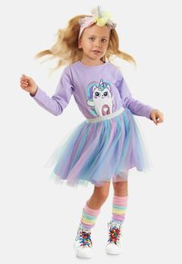 Camisa de manga larga morada con gráfico de unicornio, falda de tul en capas en colores pastel, calentadores de piernas a rayas de arcoíris y zapatillas plateadas brillantes.