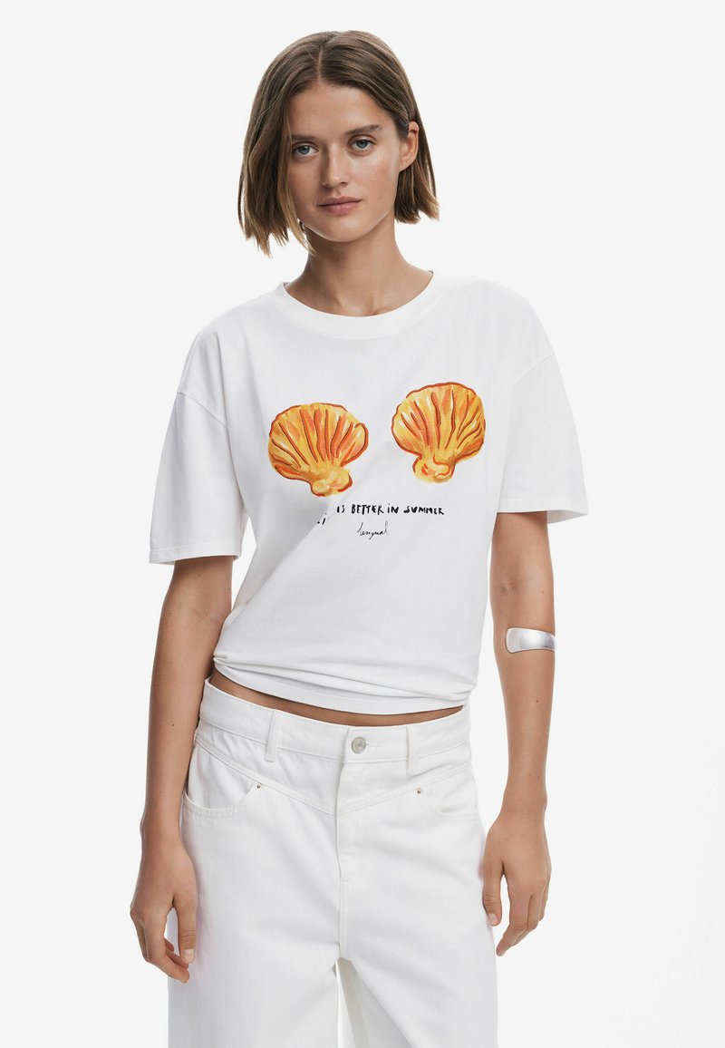 Hvid T-shirt med kort ærme, der har orange skjellgrafik og tekst. Bæres med højtkalibrerede hvide bukser, der har en glat tekstur og en afslappet pasform.