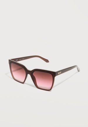 Brown oversized square sunglasses with gradient pink lenses and gold "QUAY" logo on the temple against a white background.