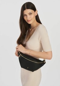 Czarna skórzana torebka o zaokrąglonym kształcie, ze złotym zamkiem błyskawicznym i łańcuszkowym paskiem. Gładka tekstura i minimalne oznakowanie z jednej strony.