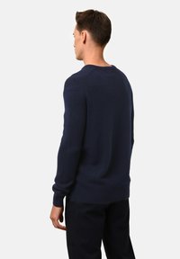 Dunkelblauer Strickpullover mit rundem Halsausschnitt und langen Ärmeln, mit gerippten Abschlüssen an den Ärmeln und am Saum, von hinten gezeigt.