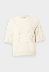 Pull tricot à manches courtes de couleur crème avec ourlets côtelés et broderie florale subtile en relief sur le devant et les épaules.