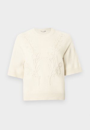 Pull tricot à manches courtes de couleur crème avec ourlets côtelés et broderie florale subtile en relief sur le devant et les épaules.