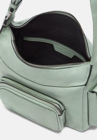 Sac en cuir vert menthe avec une surface texturée, fermeture éclair et poche avant. L'intérieur est doublé de noir et comporte des compartiments organisés.