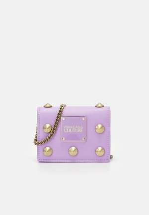 Lavendelviolette Mini-Schultertasche mit goldenen Nieten, Kettenriemen und Frontplatte mit der Aufschrift "Versace Jeans Couture."