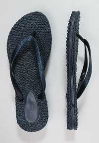 Infradito neri con suola testurizzata, dotati di fettucce nere luccicanti e un plantare liscio, offrono un design di calzature informali.